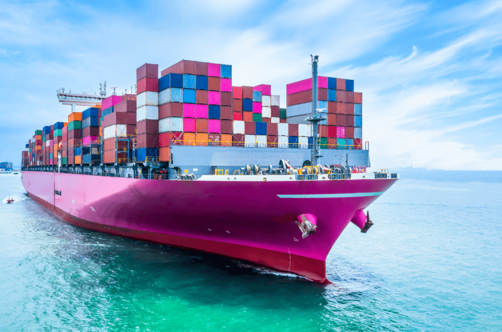 Cargo ship with a distinctive pink hull, loaded with shipping containers, symbolizing the logistics industry's shift towards environmental regulations.
