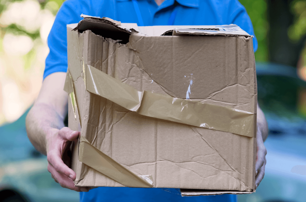Broken parcel taped together being handed over by a courier, highlighting the need for preventing damage in logistics.